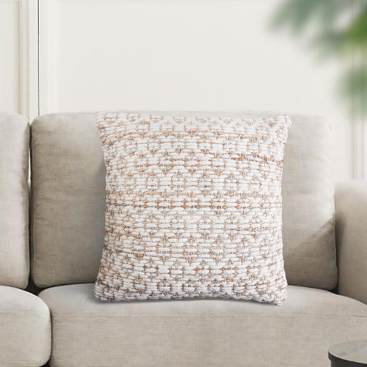 Textured throw pillow on a beige sofa with a blurred green plant in the background